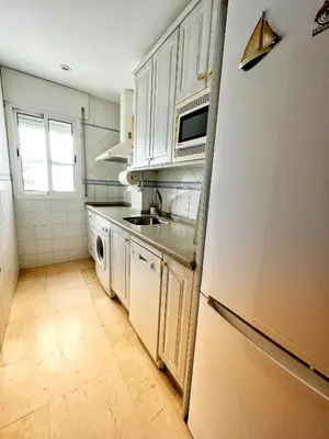 a kitchen with white cabinets and a sink and a refrigerator at Ático Good Vibes in Rota