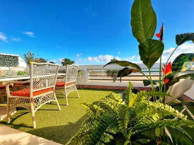 a patio with chairs and a table and some plants at Ático Good Vibes in Rota