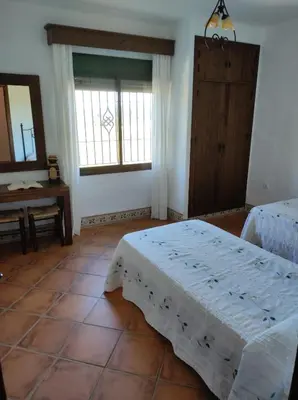 a bedroom with two beds and a table and a window at Casa Antonia in Conil de la Frontera
