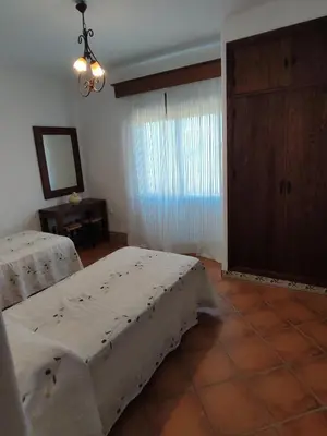 a bedroom with two beds and a mirror and a window at Casa Antonia in Conil de la Frontera