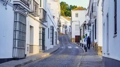 an alley with white buildings and a man walking down the street at Victoria Seis in Medina Sidonia