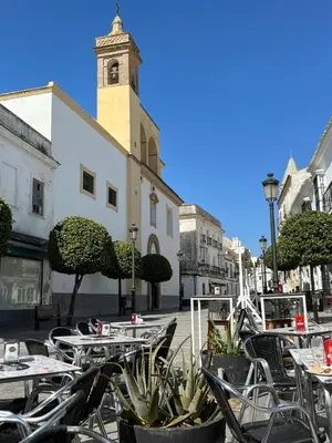 an outdoor cafe with tables and chairs and a clock tower at Victoria Seis in Medina Sidonia
