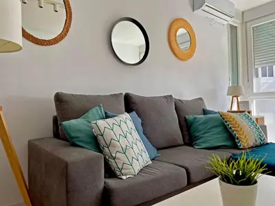 a living room with a couch with pillows and mirrors at Apartamento Aurora - Ole Solutions in El Puerto de Santa María