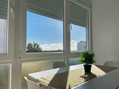a dining room with a table and two windows at Apartamento Aurora - Ole Solutions in El Puerto de Santa María