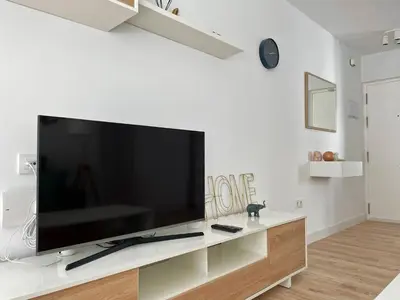 a living room with a large flat screen tv on a white wall at Apartamento Aurora - Ole Solutions in El Puerto de Santa María