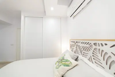 a bedroom with a white bed and a white wall at Loft en el corazón de Cádiz con opción a Parking in Cádiz