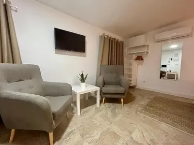 a living room with two chairs and a tv at Apartamentos Los Cabezuelos, Dream Views in Arcos de la Frontera