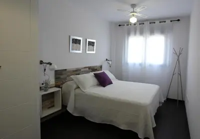 a white bedroom with a bed and a ceiling fan at Felipe Frente al rio in Sanlúcar de Barrameda