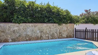 a swimming pool with a stone wall and a fence at Casa Merce Conil de la Frontera by Ruralidays in Conil de la Frontera