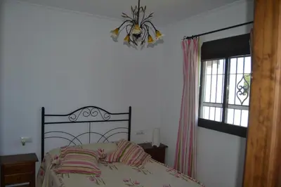 a bedroom with a bed and a window and a chandelier at El Moral in Cádiz