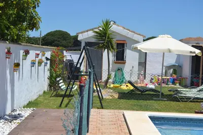 a house with a swimming pool and an umbrella at El Moral in Cádiz