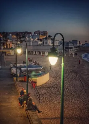 a group of people sitting on a beach at night at Apartamento Loft Puerto de Gades in Cádiz