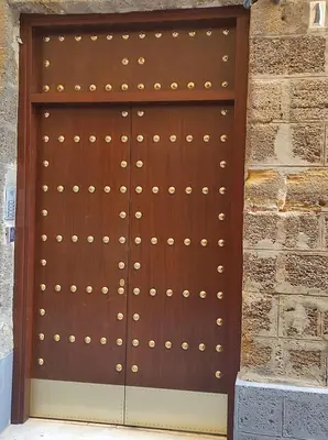 a wooden door with gold studs on a brick wall at Apartamento Loft Puerto de Gades in Cádiz