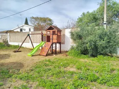 a playground with a green slide in a yard at Chiclana Mobile House - Piscina , Wi-Fi, Relax in Chiclana de la Frontera