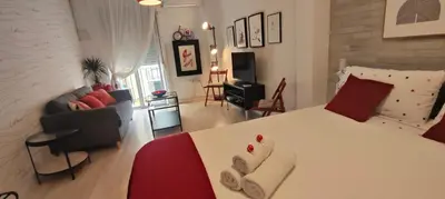 a bedroom with a white bed and a living room at El rincón de la Caleta in Cádiz