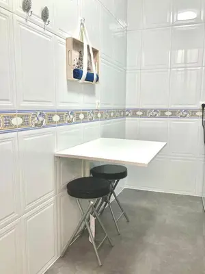 a white kitchen with two stools and a white counter at El rincón de la Caleta in Cádiz