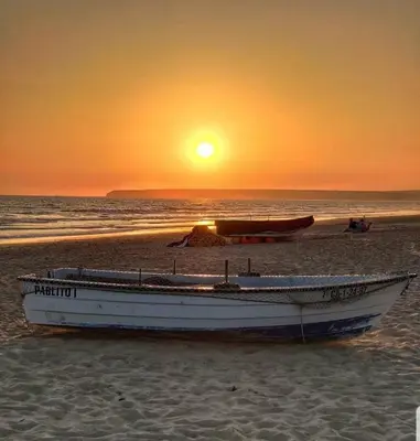 a boat sitting on the beach at sunset at El rincón de la Caleta in Cádiz