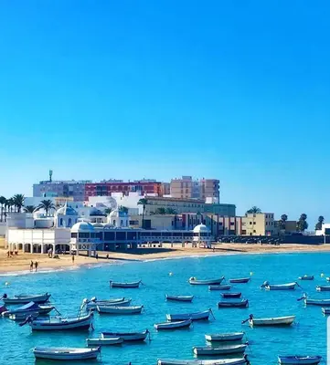 a group of boats in the water near a beach at El rincón de la Caleta in Cádiz