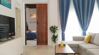 a living room with a white couch and blue curtains at Sherryflat Teatro in Jerez de la Frontera