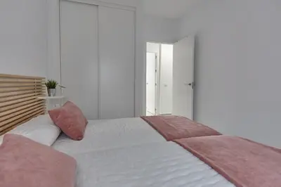 a bedroom with a large white bed with pink pillows at APTARTAMENTO DOÑANA RECIEN REFORMADO Parking gratis in Sanlúcar de Barrameda
