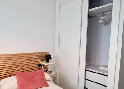 a bedroom with a bed with a red pillow and a closet at APTARTAMENTO DOÑANA RECIEN REFORMADO Parking gratis in Sanlúcar de Barrameda