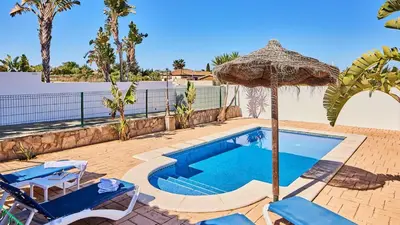 a swimming pool with an umbrella and two chairs and a swimming pool at Chalet El Cancelín Conil de la Frontera by Ruralidays in Conil de la Frontera