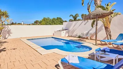 a swimming pool with blue chairs and a white wall at Chalet El Cancelín Conil de la Frontera by Ruralidays in Conil de la Frontera