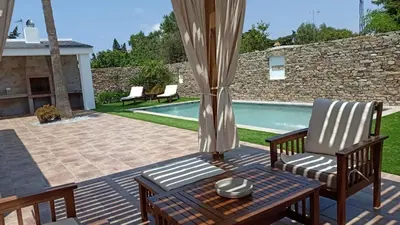 a patio with two chairs and a table and a pool at Casa La Palmera - Sólo Familias y Parejas in Conil de la Frontera