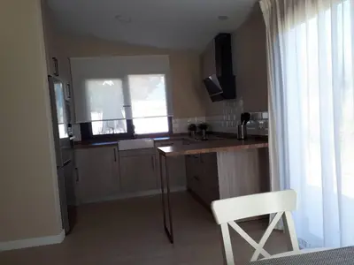 a kitchen with a table and a chair and a window at Casa La Palmera - Sólo Familias y Parejas in Conil de la Frontera