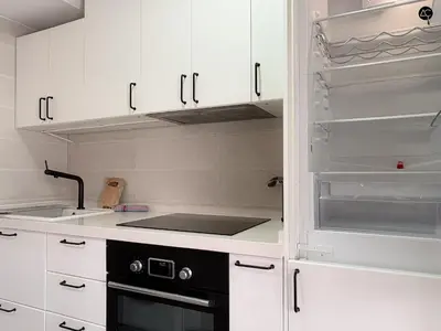 a white living room with a tv and a kitchen at ARTE Playa la Caleta Grupo AC Gestion in Cádiz