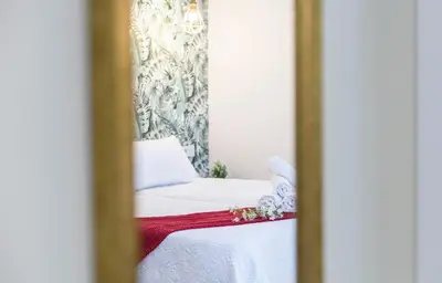 a mirror reflection of a bed with a red blanket at LalaSuites CORREDERA in Jerez de la Frontera