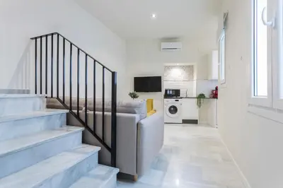 a living room with stairs and a couch and a kitchen at LalaSuites CORREDERA in Jerez de la Frontera