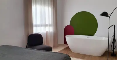 a room with a bed and a chair and a tub at ISA Cádiz Palacio de Congresos in Cádiz