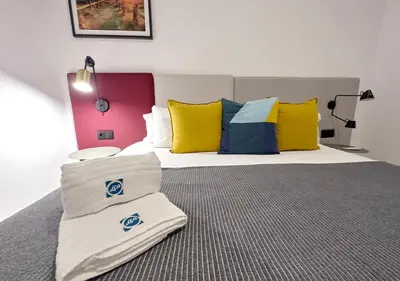 a bedroom with a large bed with colorful pillows at ISA Cádiz Palacio de Congresos in Cádiz