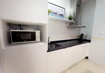 a white kitchen with a microwave and a sink at ISA Cádiz Palacio de Congresos in Cádiz
