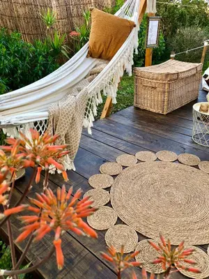 a hammock and a chair on a deck with flowers at Glamping - La Casa del Piano in Chiclana de la Frontera