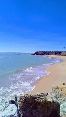 a beach with rocks and the ocean on a sunny day at JMC Apartamento CENTRO HISTÓRICO in El Puerto de Santa María