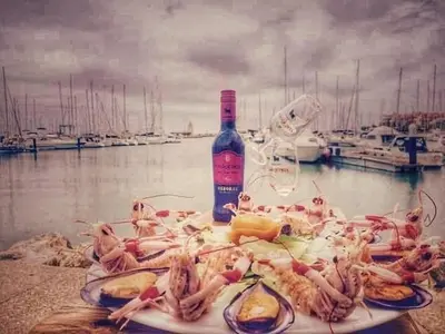 a plate of food with seafood and a bottle of wine at JMC Apartamento CENTRO HISTÓRICO in El Puerto de Santa María