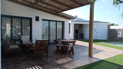 a patio with a wooden table and chairs on a patio at Falsa Pimienta - Sólo Familias y Parejas in Conil de la Frontera