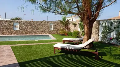 a pool with two lounge chairs and a tree at Falsa Pimienta - Sólo Familias y Parejas in Conil de la Frontera