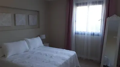 a bedroom with a white bed and a window at Falsa Pimienta - Sólo Familias y Parejas in Conil de la Frontera