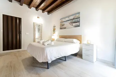 a white bedroom with a large bed and a mirror at Allo Apartments Plateros Centro Jacuzzi Comunitario in Jerez de la Frontera