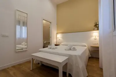 a white bedroom with a bed and a table at Apartamento Las 3 Gaviotas in Cádiz
