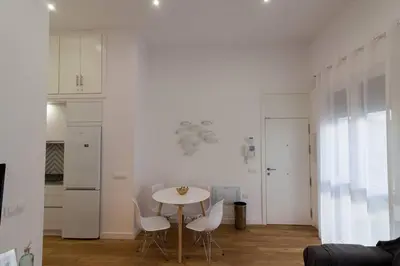 a white kitchen with a table and white chairs at Apartamento Las 3 Gaviotas in Cádiz