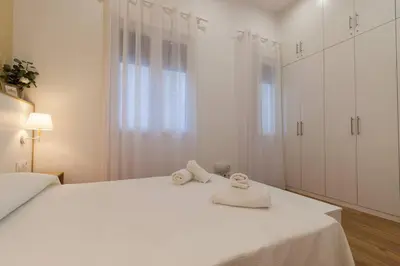 a white bedroom with two towels on a bed at Apartamento Las 3 Gaviotas in Cádiz