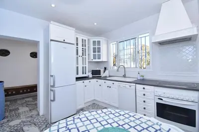 a white kitchen with a sink and a refrigerator at Villa Buganvillas, relax con piscina privada a pocos minutos de la Barrosa y Santi Petri in Chiclana de la Frontera