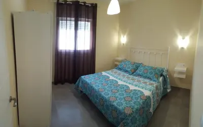 a bedroom with a bed with a blue comforter and a window at Casa Los Naranjos 3 in Cádiz