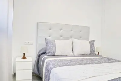 a white bedroom with a large white bed with purple pillows at Chalet del Sultan in Conil de la Frontera