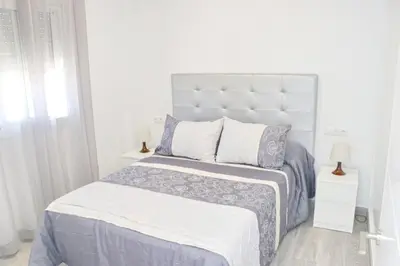 a white bedroom with a large bed and two lamps at Chalet del Sultan in Conil de la Frontera