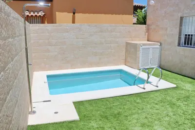 a swimming pool in a yard with grass at Chalet del Sultan in Conil de la Frontera